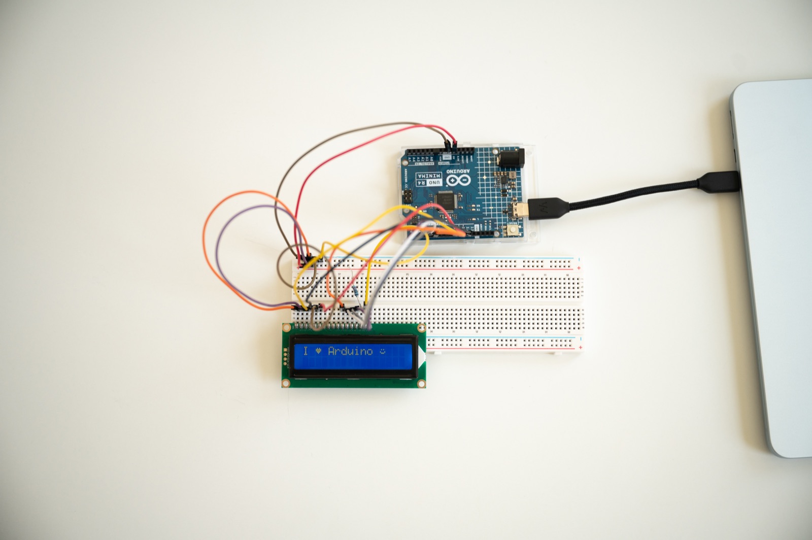 An Arduino UNO R4 wired to a breadboard and an LCD reading 'I heart Arduino'
